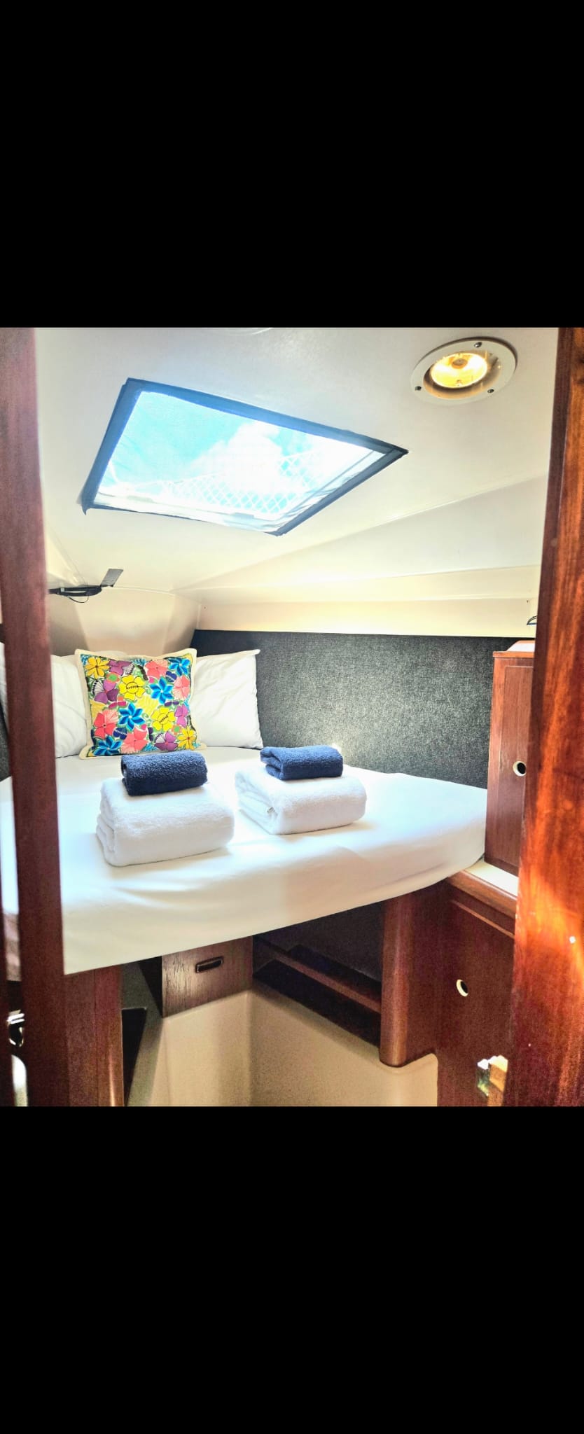 Cama en V a proa de SISU vestida con ropa blanca y toallas dobladas